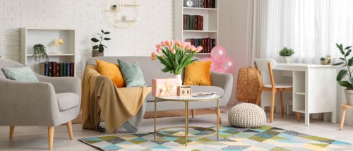 Interior of the living room in a rental apartment, with sofa and tulips in vase for International Women's Day.