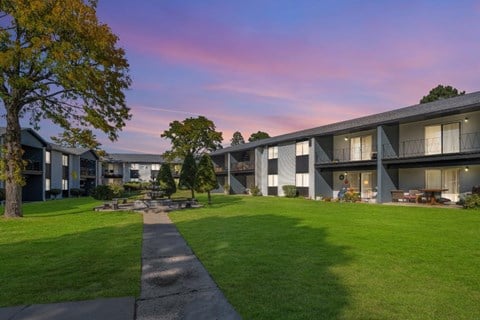 a view of an apartment complex with a lawn and a fire pit