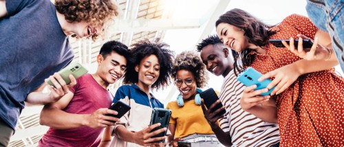 Group of Gen Z friends using their smartphones to look up information on the internet.