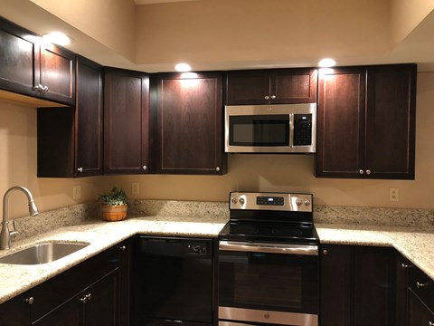 a kitchen with dark wood cabinets and a stove and a sink