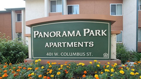 a sign for panorama park apartments in front of flowers