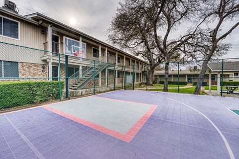 a basketball court in front of a building with stairs