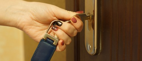 close-up of a woman's hand using a key to unlock the door