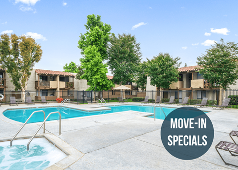 a swimming pool at an apartment complex with a sign that reads move in specials