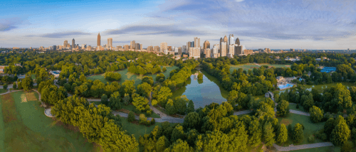 atlanta skyline with numerous tall buildings and a wide park with green trees and a body of water at the front